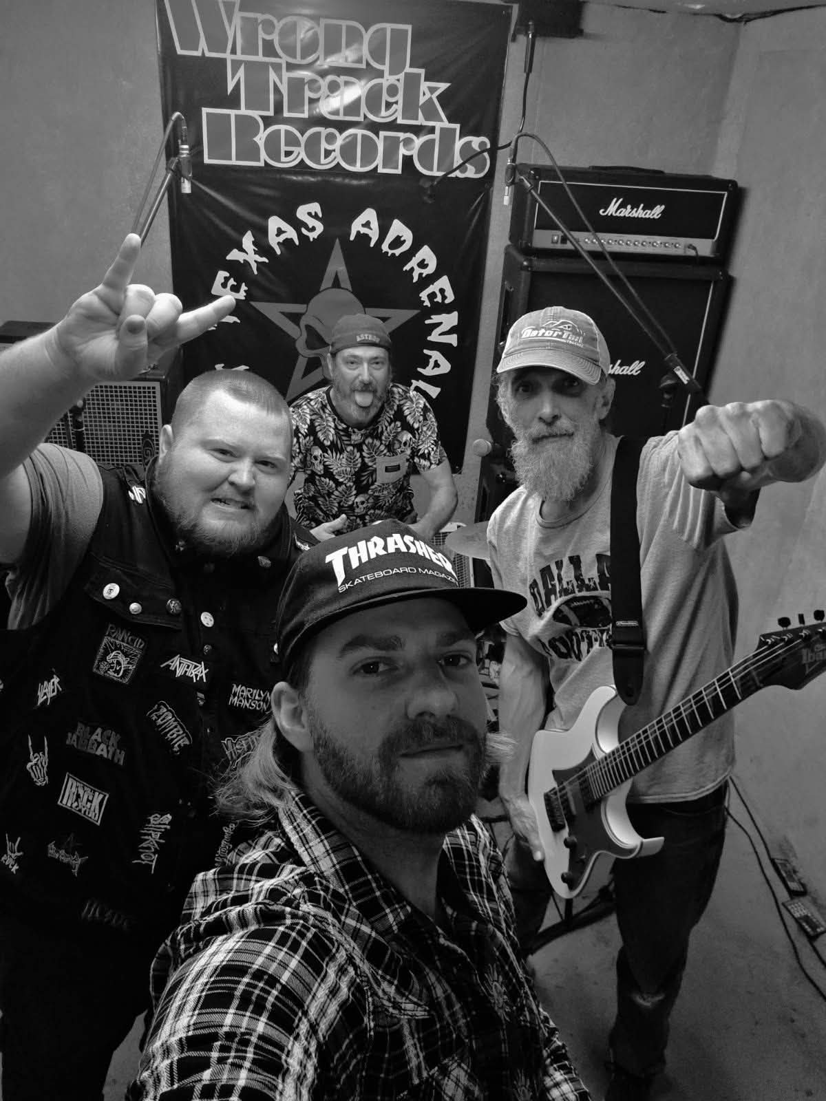 East Texas Adrenaline in the rehearsal space in front of the Wrong Track Records / East Texas Adrenaline banner, black and white